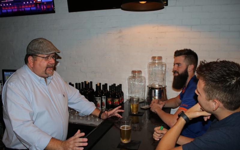 Cimaron Holt (clockwise from left), a co-owner of Prohibition, talks to patrons Stuart Fitzhugh and Tyler Turner on Tuesday night. (TONY BRITT/Lake City Reporter)