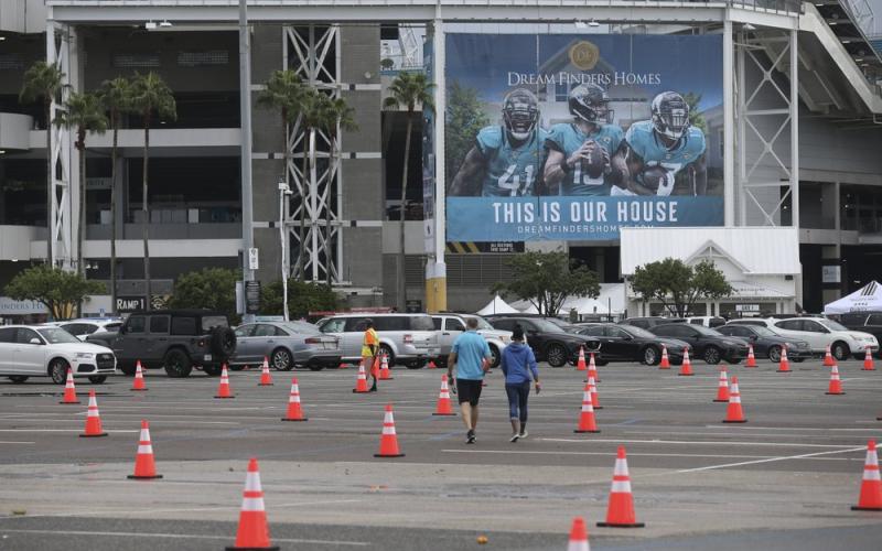 Fans walk through a parking lot with cones to social distance the cars before a game between the Jacksonville Jaguars and the Indianapolis Colts on Sept. 13 in Jacksonville. The Jacksonville Jaguars are the latest NFL team dealing with a positive COVID-19 test. The Jaguars released a statement Saturday, Oct. 17, saying a practice squad player was confirmed as testing positive for the coronavirus a day earlier. (AP FILE PHOTO)