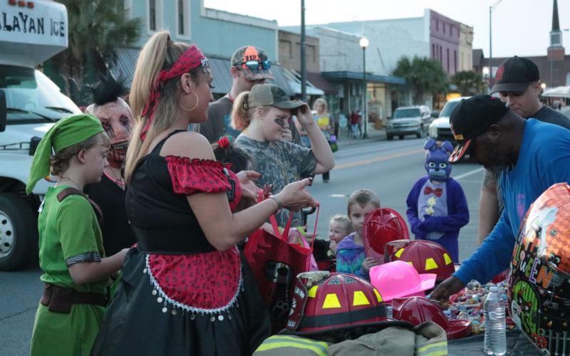 Trick-or-treaters receive candy from the Live Oak Fire Department’s booth at the Candy Carnival in downtown Live Oak last year. This year the city’s Community Redevelopment Agency is helping to sponsor a drive-in event at Heritage Park and Gardens. (SUWANNEE DEMOCRAT)