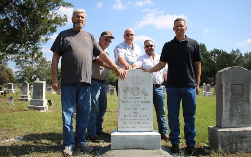 James Smith (from left), stands with Al Williams, Chuck Denmark, Jordan Thrasher and Derek Smith around the headstone of Thomas C. Strange, a Columbia County resident who was reportedly the first Confederate soldier killed in Florida during the Civil War. The Smiths are descendants of Strange, while Williams, Denmark and Thrasher serve as trustees for the cemetery. (TONY BRITT/Lake City Reporter)