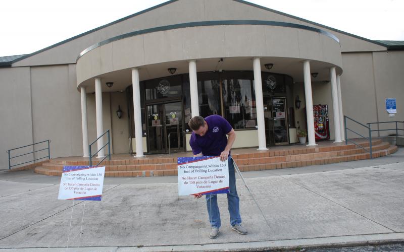 Kent Banner, an elections office staff member, prepares for early voting by adding signs in front of the supervisor of elections office. (TONY BRITT/Lake City Reporter)