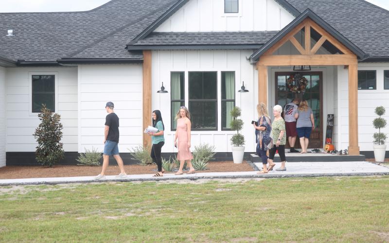 A group of visitors exit the house at 567 NW High Point Drive Saturday while others prepare to enter on the 2020 Parade of Homes. The delayed event featured 10 newly constructed houses around Columbia County and drew a steady crowd both Saturday and Sunday. (JAMIE WACHTER/Lake City Reporter)