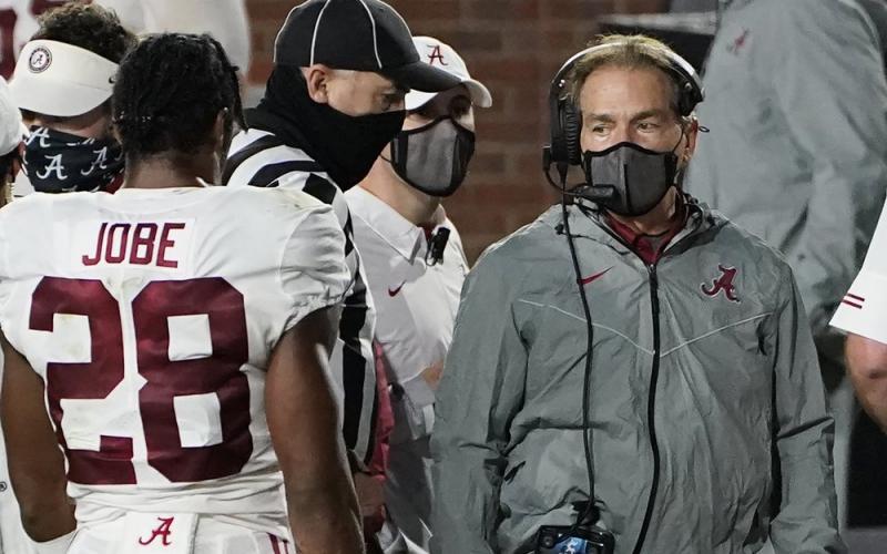 A masked Alabama coach Nick Saban speaks with defensive back Josh Jobe (28) during a game against Mississippi on Oct. 2 in Oxford, Miss. (ROGELIO V. SOLIS/Associated Press)