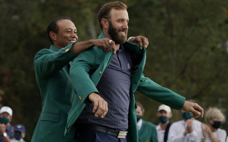 Tiger Woods helps Masters' champion Dustin Johnson with his green jacket after his victory at the Masters on Sunday in Augusta, Ga. (AP Photo/CHARLIE RIEDEL/Associated Press)