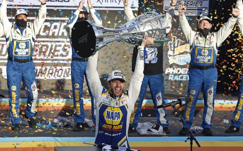 Chase Elliott holds up the season championship trophy as he celebrates with his race crew in Victory Lane after winning a NASCAR Cup Series auto race at Phoenix Raceway on Sunday