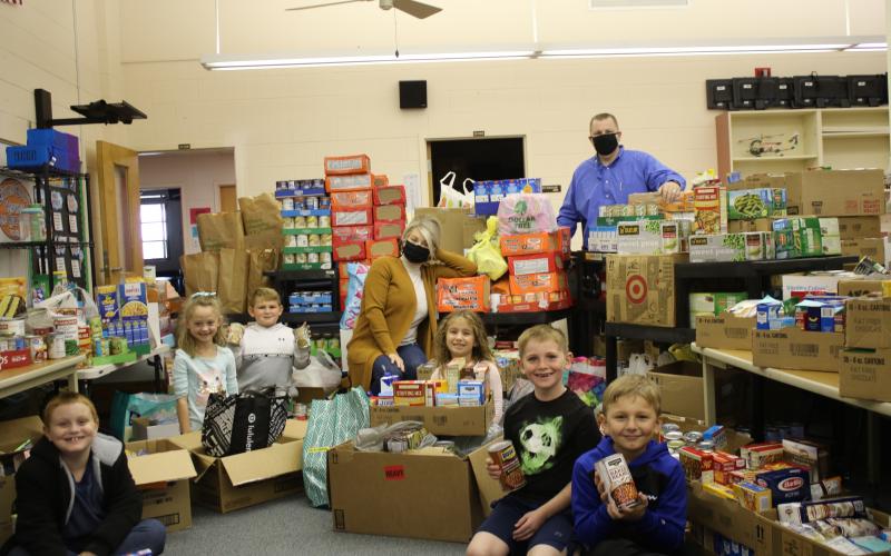 Columbia City Elementary students James Thomas (from left), Reese Wilson, Brantley Robinson, Olivia Medeiros, Hunter West and Luke Jordan show off food donations collected with Vickie Tuell, CCE guidance counselor, and Jonathan Jordan, CCE principal. (TONY BRITT/Lake City Reporter)