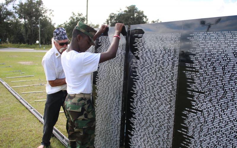 Thomas “Tom” Johnson (from left) and Clayton Fleming, erect a portion of the Vietnam Traveling Memorial Wall Thursday morning. (TONY BRITT/Lake City Reporter)