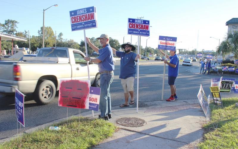 Phillip Crenshaw, (from left) James Crenshaw and Todd Sampson wave to passing motorists along U.S. Highway 90 in front of the Supervisor of Elections office Tuesday afternoon. Both James Crenshaw and Sampson were vying for the Lake City Council District 13 seat vacated by a retiring councilwoman. (TODD WILSON/Lake City Reporter)