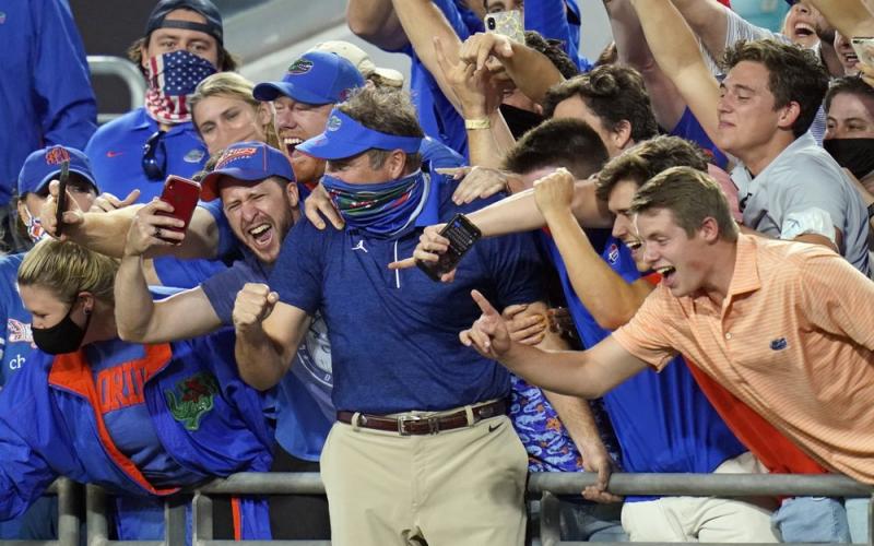 Florida head coach Dan Mullen, center, celebrate with fans in the stands after the Gators defeated Georgia on Nov. 7 in Jacksonville. (JOHN RAOUX/Associated Press)