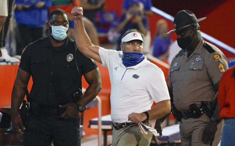 Florida head coach Dan Mullen, center, raises his fist to cheering Florida fans after an argument at the end of the first half as he was escorted to the locker room by law enforcement officers during Saturday's game against Missouri in Gainesville. (JOHN RAOUX/Associated Press)