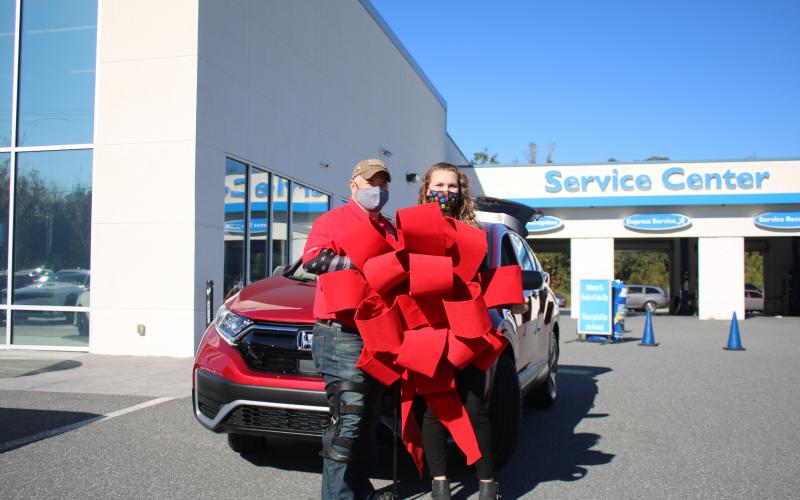 Veteran Jesse Todd, a retired U.S. Army Staff Sergeant who was wounded in Afghanistan, stands with his wife Julia Todd, as the two hold a red ribbon in front of their new 2020 Honda CR-V. Todd, the recipient of a Purple Heart, was given the payment-free vehicle through the Military Warriors Support Foundation’s Transportation4Heroes program Tuesday afternoon at Honda of Lake City. (TONY BRITT/Lake City Reporter)