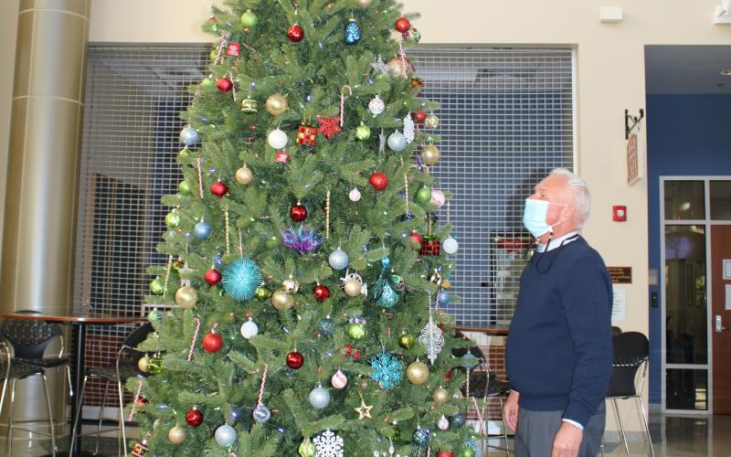Mike McKee, Florida Gateway College executive director of media/public information, adjusts ornaments on a Christmas tree at the Wilson Rivers Library Wednesday afternoon. FGC will host its inaugural  Winter Wonderland event 5-9 p.m. on Saturday, Dec. 12. (TONY BRITT/Lake City Reporter)