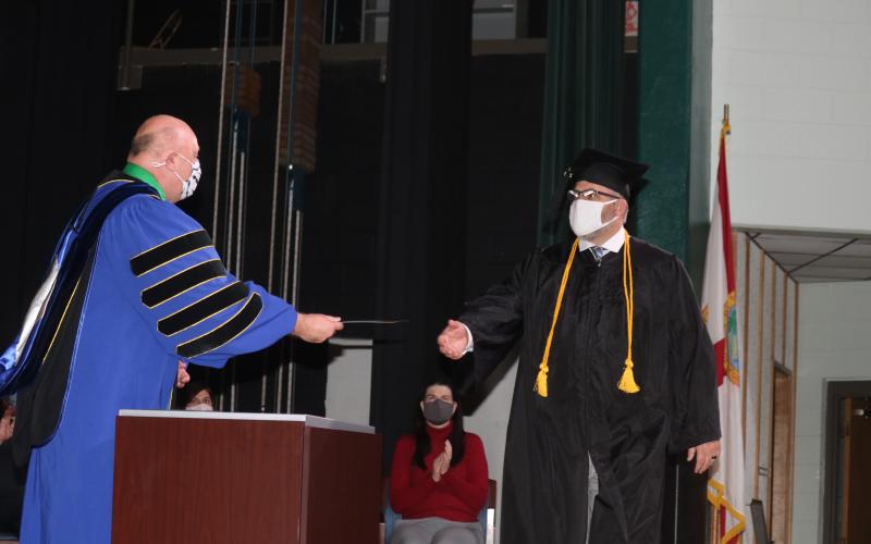 Lawrence Barrett (left), Florida Gateway College President, gives Kevin Doorman his water services bachelors degree during commencement exercises Thursday evening at the college. (TONY BRITT/Lake City Reporter)