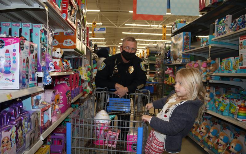 Ryleigh Harden gets a ride on a shopping cart from Lake City Police Department Lt. Andy Miles while Christmas shopping during the Shop with a Cop program Wednesday morning at Walmart. Thirty local children were able to go Christmas shopping with LCPD officers during the event. (TONY BRITT/Lake City Reporter)