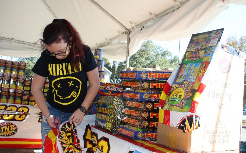 Kenzie Dungan cuts holes in a banner to allow wind to flow through the banner as she and other FFA students and volunteers prepared to open the Columbia FFA Fireworks stand Monday afternoon. Proceeds raised from the fireworks sales will benefit students in the Columbia FFA chapters. (TONY BRITT/Lake City Reporter)