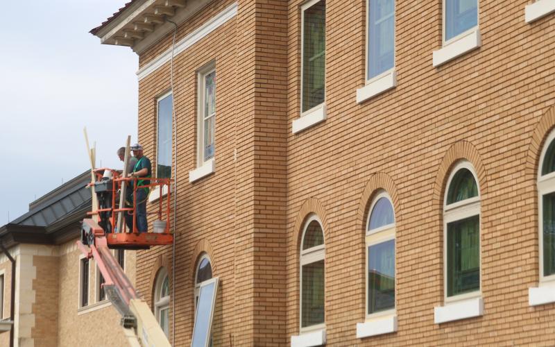 Workers from North Florida Glass work last week on placing new windows over the stained glass windows at the First Baptist Church of Lake City. (JAMIE WACHTER/Lake City Reporter)