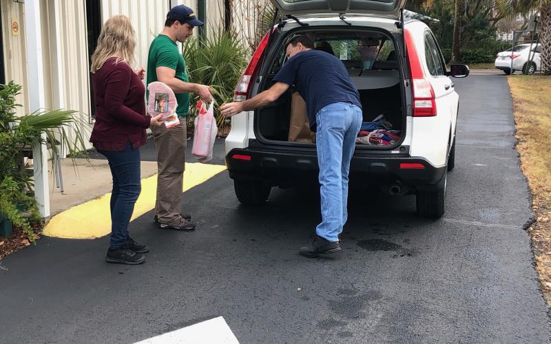 Sadie House (from left), Christian Service Center assistant director, Ben Walker and Mike House load goods into a Christian Service Center client’s vehicle Monday. (COURTESY)