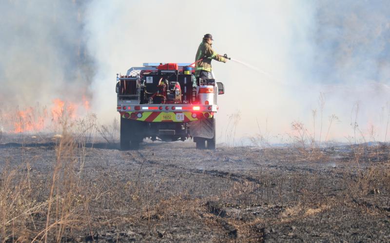 A Columbia Fire Rescue truck heads towards a wall of smoke and flames Tuesday afternoon while fighting a brush fire on Northwest The Lords Court near the Suwannee County border. (TONY BRITT/Lake City Reporter)