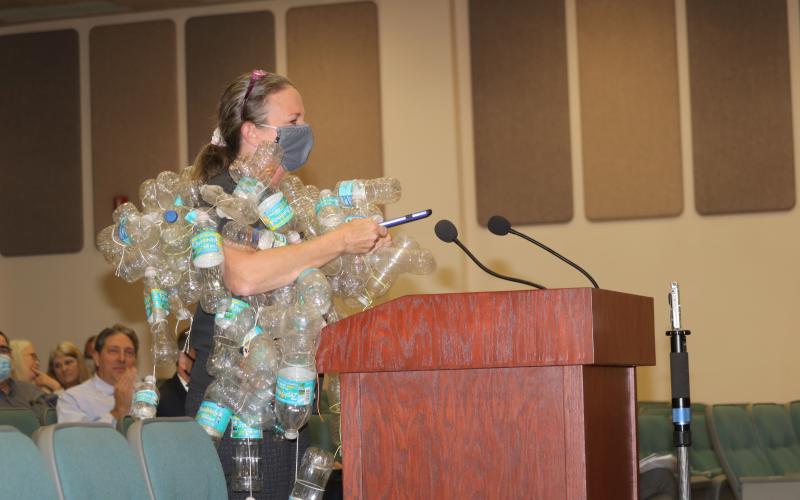 Merrillee Malwitz-Jipson, a Fort White resident, wears a collection of used plastic bottled water containers as she addressed the legislative delegation Tuesday in the Columbia County School Board Administrative Complex Auditorium. Malwitz-Jipson said she wore the bottles to show legislators an example of waste, noting the water bottles will pollute the environment for years. (TONY BRITT/Lake City Reporter)