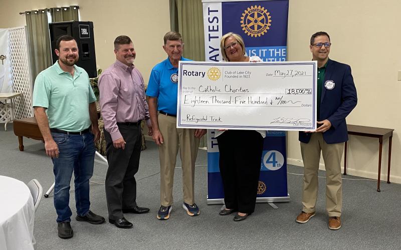 Lake City Rotarians Chase Moses (from left), Robert Turbeville, Joseph Persons, Catholic Charities Executive Director Suzanne Edwards and Rotary President Lee Pinchouck pose with a donation check made by several individuals and other Rotary Club members to help purchase a new refrigerated truck needed for daily use by Catholic Charities. Not pictured are donating Rotarians Steve Smith and Fred Koberlein Jr. A total of $19,250 was raised by the Lake City Rotary Club. (TODD WILSON/Lake City Reporter)