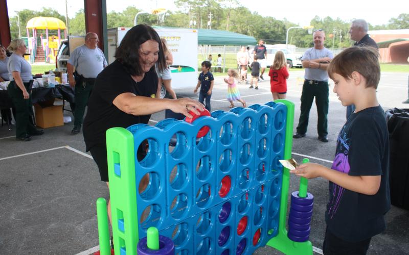 Jean Hamm (left) plays Connect Four with her grandson, Titan Turner, 9, during the Columbia County Sheriff’s Office Summer Nights event Friday night at Five Points Elementary School. (TONY BRITT/Lake City Reporter)