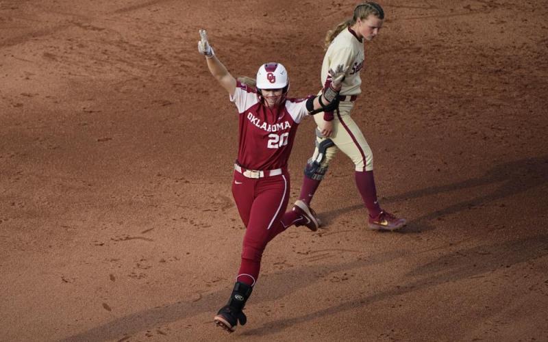 Oklahoma's Jana Johns (20) celebrates as she runs past Florida State's Josie Muffley after hitting a home run during the third inning of Game 2 of the Women's College World Series softball championship series on Wednesday in Oklahoma City. (SUE OGROCKI/Associated Press)