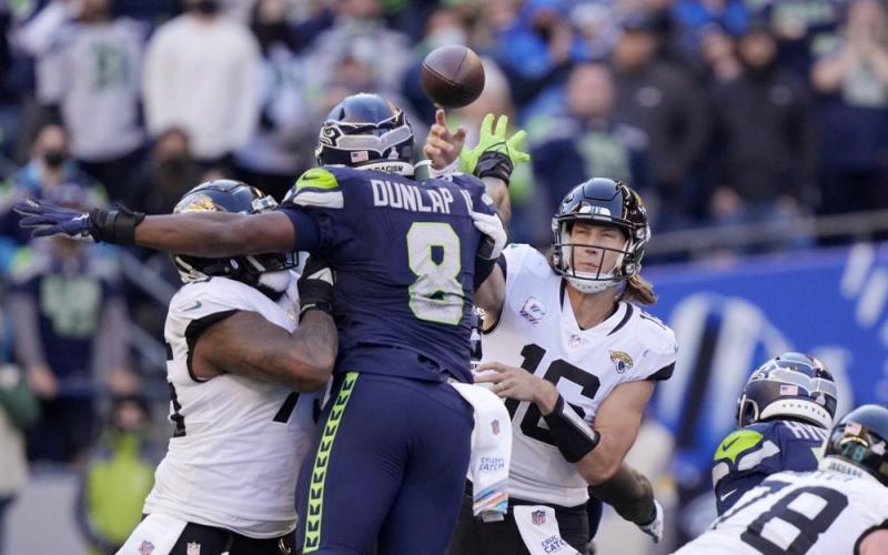 Seattle Seahawks defensive end Carlos Dunlap puts a hand up as he tries to deflect a pass from Jacksonville Jaguars quarterback Trevor Lawrence on Sunday in Seattle. (STEPHEN BRASHEAR/Associated Press)