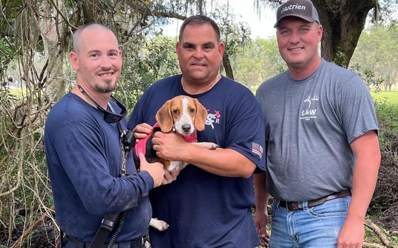 Suwannee County Fire Rescue’s Lt. Jacob Doyle (from left), Tad Cervantes and Adam McCook with Emmy after rescuing the six-month-old beagle puppy from a sinkhole Saturday. (COURTESY)