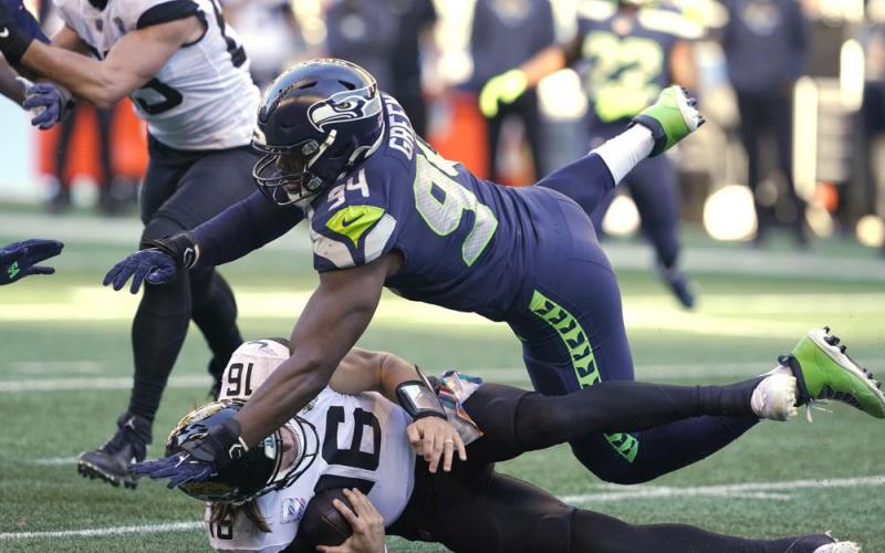 Seattle Seahawks' Rasheem Green tumbles across Jacksonville Jaguars quarterback Trevor Lawrence after Lawrence kept the ball on a carry during Sunday’s game Sunday in Seattle. (TED S. WARREN/Associated Press)