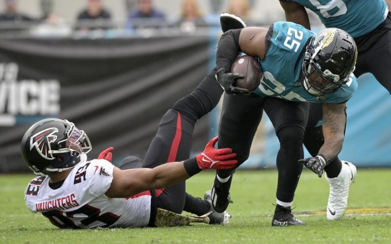 Jacksonville Jaguars running back James Robinson is tackled by Atlanta Falcons linebacker James Vaughters on Nov. 28 in Jacksonville. (PHELAN M. EBENHACK/Associated Press)