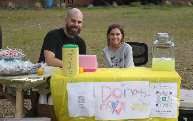Corey Burk (left) and Lexi Mccardle sit behind Lexi’s lemonade stand Thursday afternoon. (MORGAN MCMULLEN/Lake City Reporter)