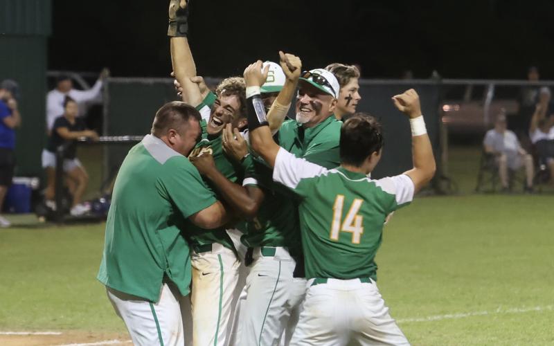 Suwannee coaches and player swarm Carston Palmer after he scored the game-winning run against Clay in the Region 1-4A semifinals on Saturday night. (PAUL BUCHANAN/Special to the Reporter)