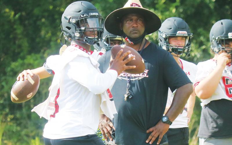 Former Fort White quarterback Tyler Jefferson drops back to pass while former head coach Demetric Jackson looks on during a practice in 2020. (FILE)