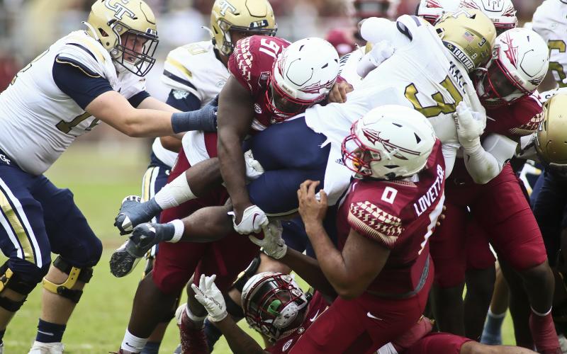Florida State defenders, including defensive tackle Fabien Lovett (0), lift Georgia Tech running back Hassan Hall (3) off the ground as he tries to runs the ball on Saturday in Tallahassee. (PHIL SEARS/Associated Press)