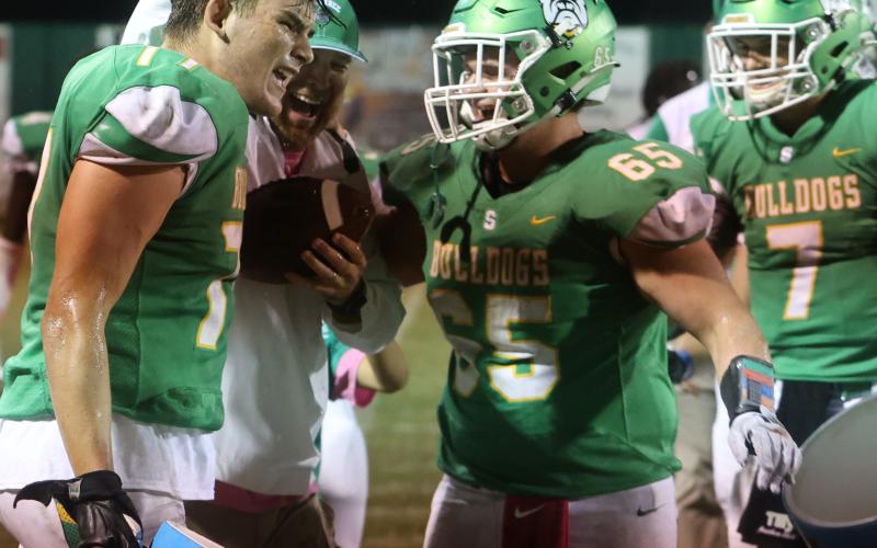 Suwannee head coach Kyler Hall laughs with offensive lineman Taylon Jones (left) and offensive lineman Andrew Harrell (right) after the team gave Hall a cooler bath following the Bulldogs’ 36-7 win over Madison County on Friday. (PAUL BUCHANAN/Special to the Reporter)