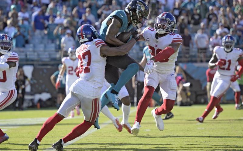 Jacksonville Jaguars wide receiver Christian Kirk (13) is stopped by New York Giants cornerback Fabian Moreau (37) and safety Julian Love (20) during Sunday's game in Jacksonville. (PHELAN M. EBENHACK/Associated Press)