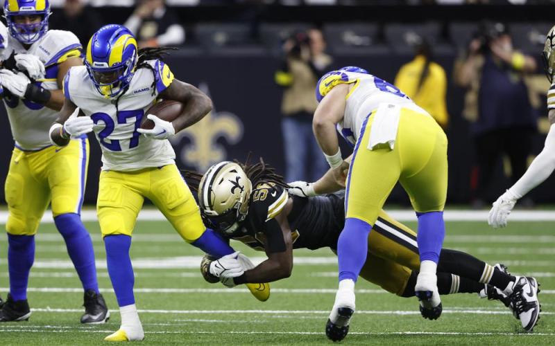 Los Angeles Rams running back Darrell Henderson Jr. carries the ball as New Orleans Saints linebacker Demario Davis holds on during Sunday’s game in New Orleans. (BUTCH DILL/Associated Press)