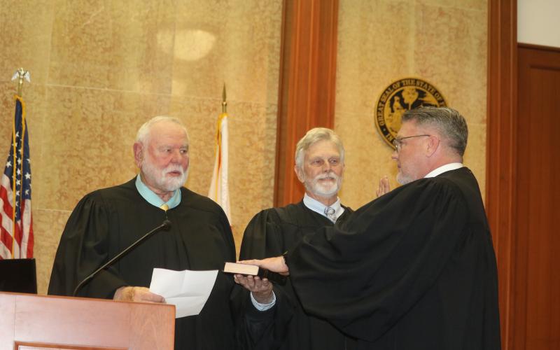 Circuit Judge Fred Koberlein Jr. (right) is sworn in Thursday by his father, Senior Judge Fred Koberlein Sr. (left), as retired County Judge Tom Coleman holds the Bible during an investiture ceremony at the Columbia County Courthouse. (TONY BRITT/Lake City Reporter)