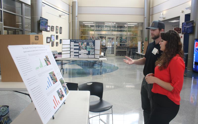 Tristian Huff (from left) and Stevee Boyd look over science fair projects as 2023 Suwannee Valley Regional Science and Engineering Fair judges on Thursday after at the Wilson S. Rivers Media Center on the Florida Gateway campus. Winners will be announced today at the Levy Performing Arts Center. (TONY BRITT/Lake City Reporter)