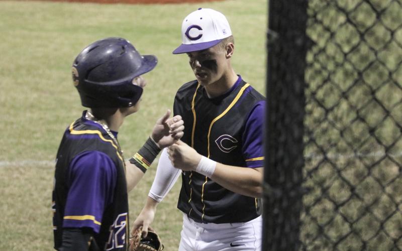 Columbia’s Hayden Gustavson (right) fist bumps Camdon Frier after Frier scored a run against Gainesville on Friday night. (JORDAN KROEGER/Lake City Reporter)