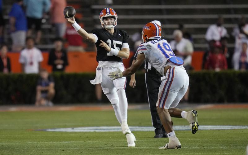 Florida quarterback Graham Mertz (left) throws a pass as he is pressured by edge T.J. Searcy (19) the team's annual Orange and Blue spring game on Thursday in Gainesville. (JOHN RAOUX/Associated Press)