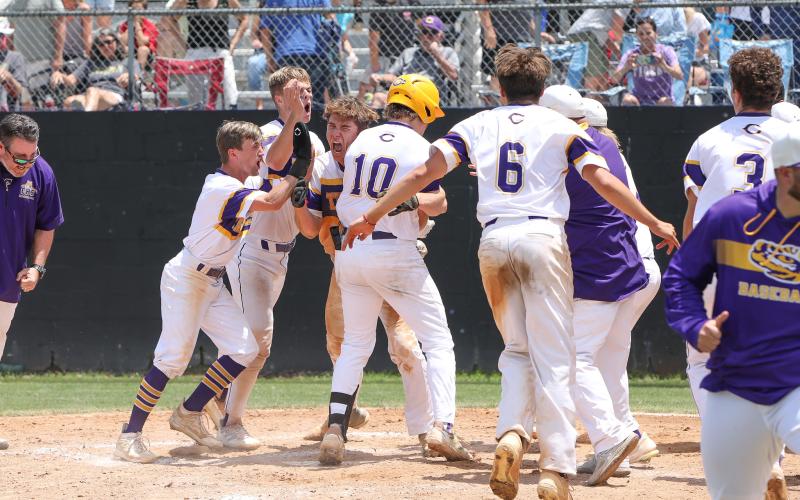 Columbia players swarm Josh Fernald at home plate after Fernald hit a walk-off grand slam against Lincoln on Saturday in the Region 1-5A semifinals. The Tigers won 8-4. (BRENT KUYKENDALL/Lake City Reporter)