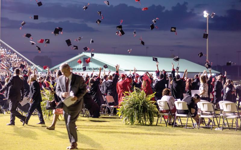 Fort White High graduates toss their caps in the air at the end of Friday’s commencement ceremony at Arrowhead Stadium as Superintendent Lex Carswell (foreground) walks off the field. (RAY CARPENTER/Special to the Reporter)