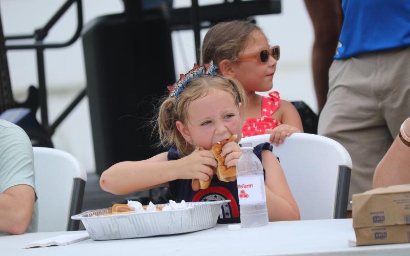 Rayva Boyle, 8, takes part in the hot dog eating contest Saturday at the Rotary Club of Lake City Downtown Independence Day celebration. Boyle stuffed down five hot dogs in the five-minute contest using a hot dog in each hand approach. (JAMIE WACHTER/Lake City Reporter)