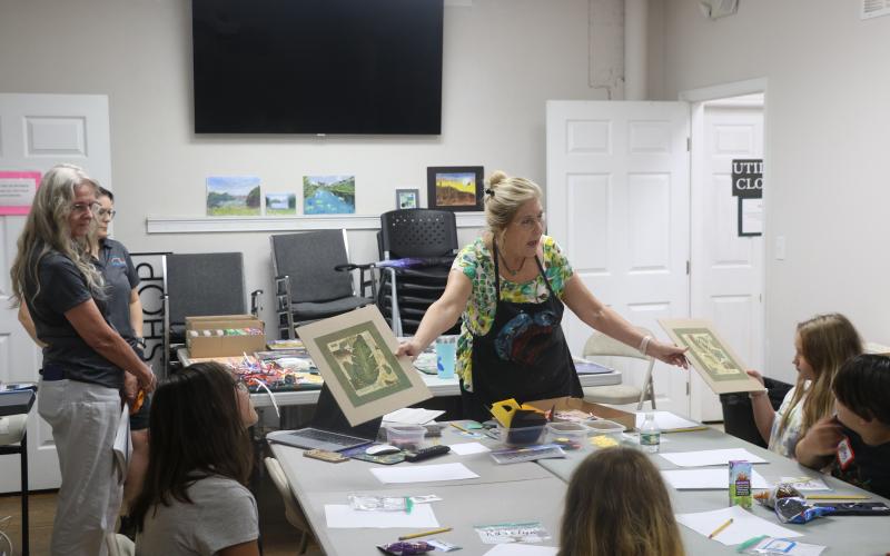 Laura Hunter-Null with the Gateway Art Gallery shows collages to students in an art literacy class Wednesday. The Gallery has partnered with Altrusa of Lake City on the program to teach literacy skills to children. (MORGAN MCMULLEN/Lake City Reporter)