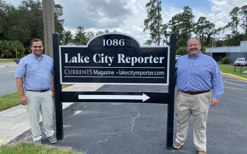 Lake City Reporter Editor Jamie Wachter (left) and Publisher Todd Wilson stand beside the newspaper’s relocated sign street side at 1086 SW Main Blvd., where the newspaper has relocated to Suite 103 of the former Social Security office complex. The Reporter completed its move earlier this month after selling its 11,000 square foot building on Duval Street downtown to Columbia County earlier this year. The signs were moved earlier this week. (JULIA GASPARRINI/Lake City Reporter)