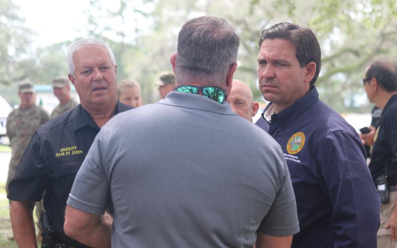 Gov. Ron DeSantis (right) talks with Suwannee County Commission Chairman Franklin White and Sheriff Sam St. John Friday afternoon in Live Oak. (JAMIE WACHTER/Lake City Reporter)