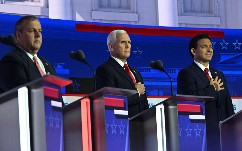 Chris Christie (left) and Florida Gov. Ron DeSantis (right) stand for the national anthem with former Vice President Mike Pence at the GOP debate Aug. 23. (PEDRO UGARTE/AFP/Getty Images/TNS)