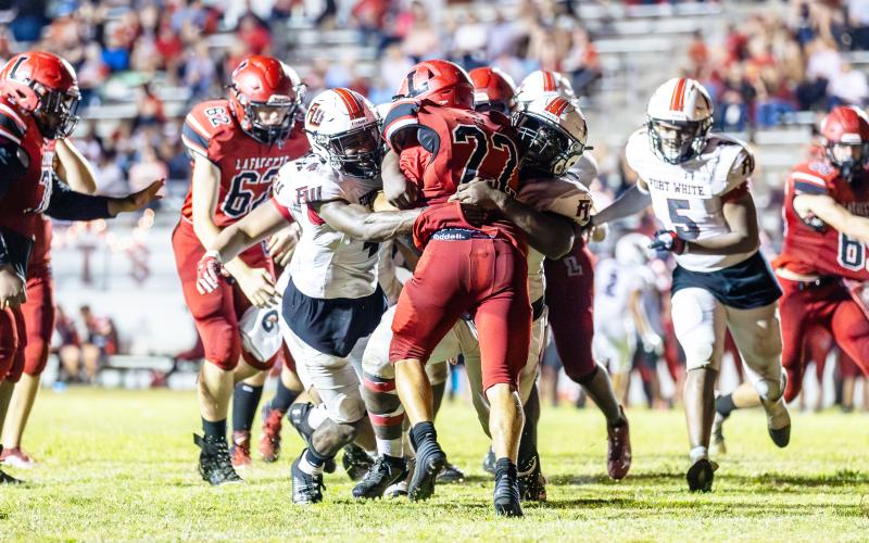 Maliki Clark (4) and the Fort White defense tackle Lafayette running back Tavis Hutson last Friday. (JACK HOWDESHELL/Special to the Reporter)