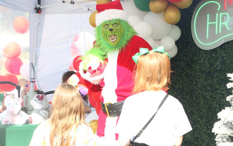 The Grinch reacts to a pair of children approaching him at the City of Lake City’s Holiday Market in downtown Lake City on Saturday. (MORGAN MCMULLEN/Lake City Reporter)